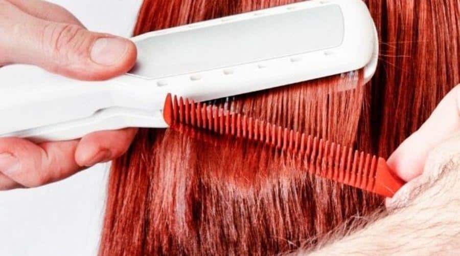 person using white straightener on red hair to kill head lice